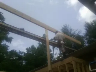 Carpenter setting a ridge beam over a new addition frame — Ice Dam Removal by Roofing Brothers in Rives