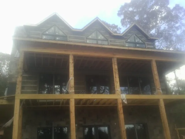 Dormers and porch framing on a large log home under construction — Roof Coating work by our crew in Rives