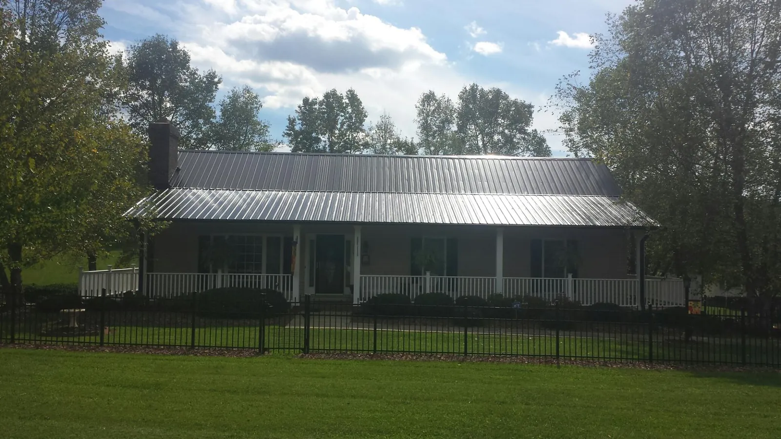 Gray metal roof on a brick ranch with a full width front porch — Gutter Guard Installation work by our crew in Rives