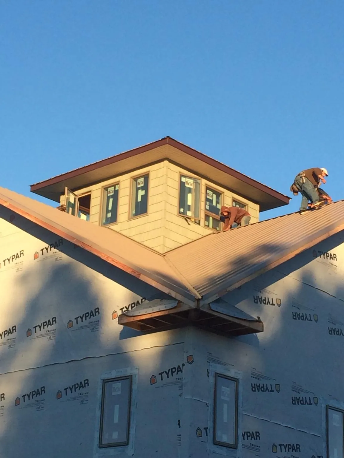 Roofers working around a rooftop cupola on a new metal roof at sunset — Roof Waterproofing in Rives by Roofing Brothers